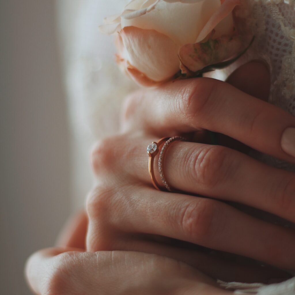 A closeup shot of a bride wearing a beautiful diamond ring and holding a rose